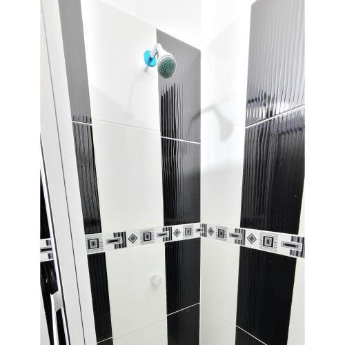 a shower with black and white tile and a shower head at Posada Campestre en Doradal in Puerto Triunfo