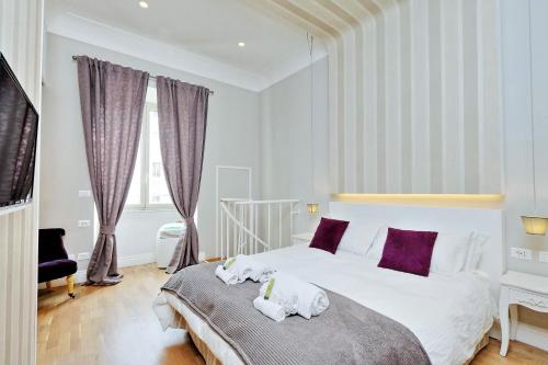 a bedroom with a large white bed with purple pillows at Elegant Suite Vibia 300 mt from Colosseum in Rome