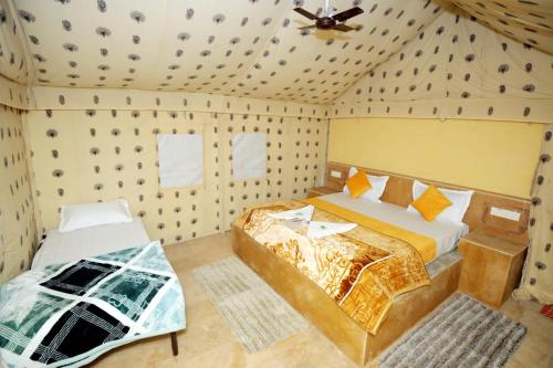 a bedroom with two beds and a ceiling fan at Mehta Desert camp Sam sand Dunes Jaisalmer in Jāmb