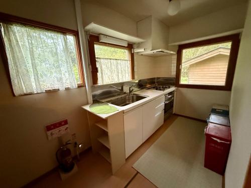a small kitchen with a sink and two windows at Wakaranai Lodge Tomamu in Shimukappu