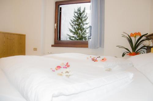 two white beds in a bedroom with a window at Hotel Casa Alpina - Alpin Haus in Selva di Val Gardena