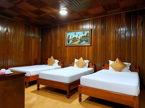 two beds in a room with wood paneling at ASANA Villas in Siem Reap