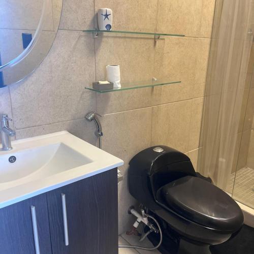 a bathroom with a black toilet and a sink at Apartamento Ocean View in La Chumicosa