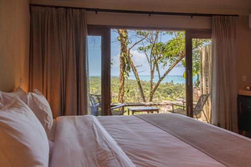 a bedroom with a bed and a large window at Vila Figo in Trancoso