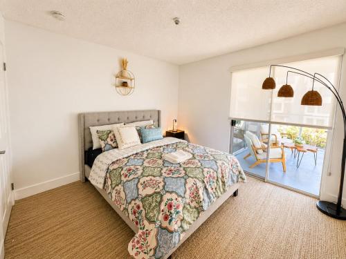 a bedroom with a bed and a balcony with a table at mamihomes redondo beach in Redondo Beach