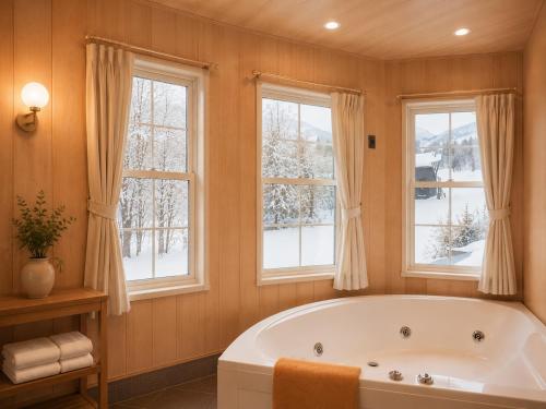a bathroom with a tub and two windows at Hakuba Sun Valley Hotel in Hakuba