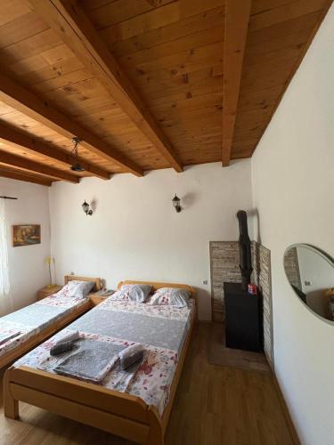 two beds in a room with wooden ceilings at Kuća za odmor in Trebinje