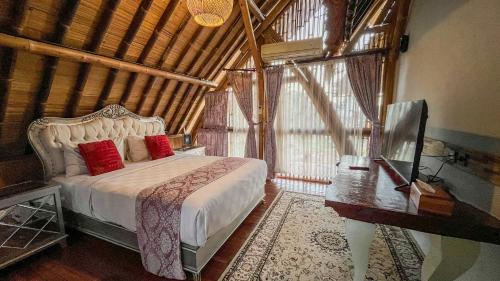 a bedroom with a bed with red pillows next to a window at The Kharma Villas Yogyakarta in Yogyakarta