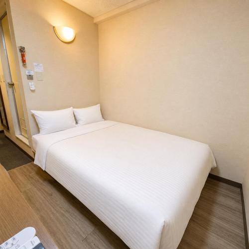 a large white bed in a small room at Business Hotel Goi Hills in Ichihara