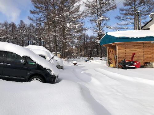 a car parked in the snow next to a cabin at Alpha Live Madarao in Madarao Kogen