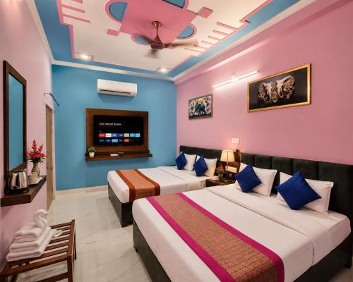 two beds in a room with blue and pink walls at Viraj Guest House in Ayodhya