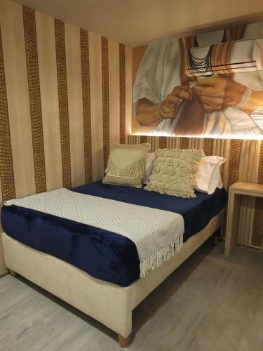 a bedroom with a bed with a painting on the wall at Casa Tayrona Suites in Medellín