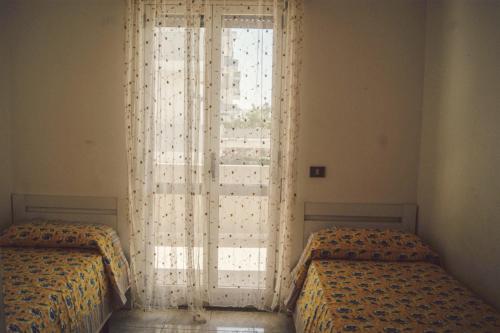 ガリポリにあるAppartamento Feniceのベッドルーム1室(ベッド2台、窓付)