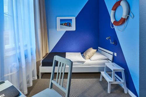 a small blue room with a bed and a chair at Hotel 38 in Berlin