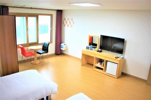 a living room with a television and a table with chairs at Samda Hostel in Jeju