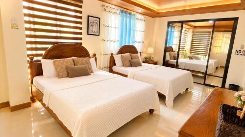 a bedroom with two beds and a mirror at Villa Lourdes in Alaminos