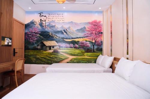 two beds in a room with a painting on the wall at Thong Dong homestay&villas in Ninh Binh