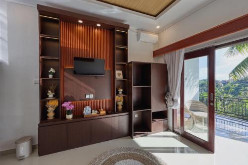 a living room with a tv and a sliding glass door at Kelingking Puri Suci Villa in Nusa Penida