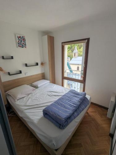 a bed in a room with a large window at Appartement au centre de Barèges in Barèges