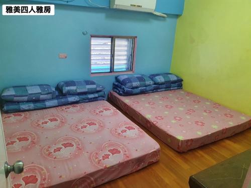 two beds in a room next to a window at 蘭嶼雅美民宿 in Yeh-yin