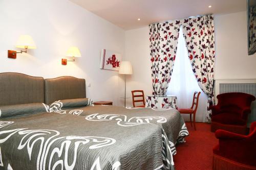 a hotel room with a bed and a chair at Hôtel d'Etigny in Luchon