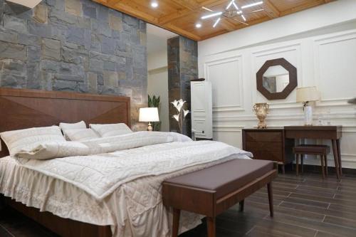 a bedroom with a large bed and a desk at ZAR Luxury Suites in Murree