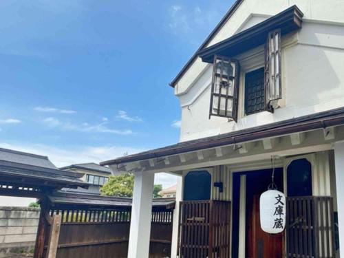 a white house with blue trim and a porch at Iizukatei in Nakagawa