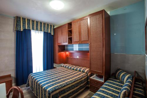 a bedroom with a bed and a cabinet and a window at Hotel Colombo in Lido di Jesolo