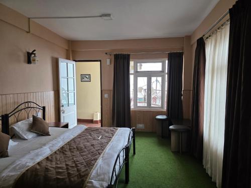 a bedroom with a bed and a large window at Sri Vrindavan Guest House Pure Veg in Darjeeling