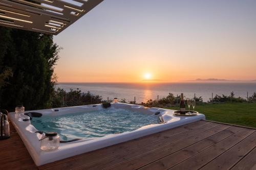a hot tub on a deck with the sunset in the background at Monte Smith Luxury Villas in Rhodes Town