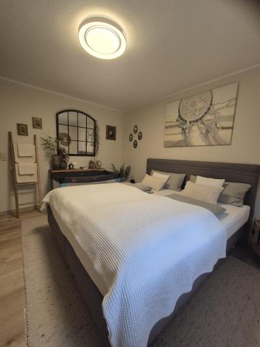 a large white bed in a bedroom with a table at Ferienhaus im Heideparadies Handeloh-Höckel in Handeloh