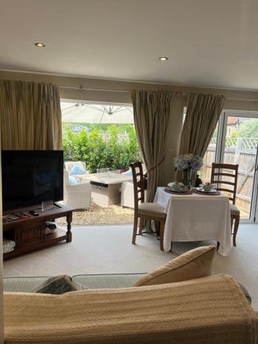 a living room with a television and a table and chairs at Highcroft House in Corsham