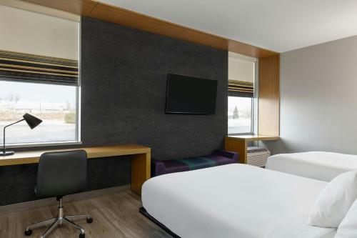a hotel room with two beds and a desk and a tv at Aloft by Marriott Green Bay in Green Bay