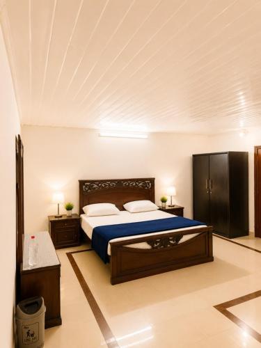 a bedroom with a large bed with blue sheets at Canopy Court Farmhouse Murree in Bhurban
