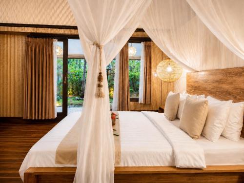 a bedroom with a white bed with a canopy at Meno Dream Resort in Gili Meno