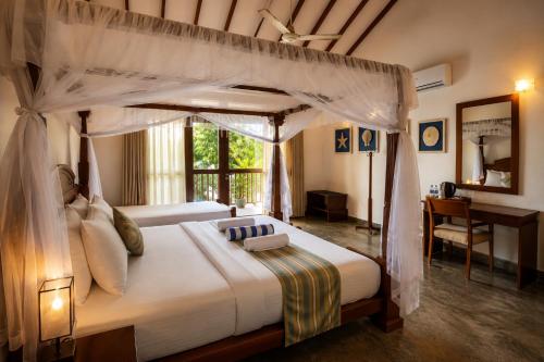 a bedroom with a canopy bed and a desk at Surf Bay Villa Weligama in Pelena