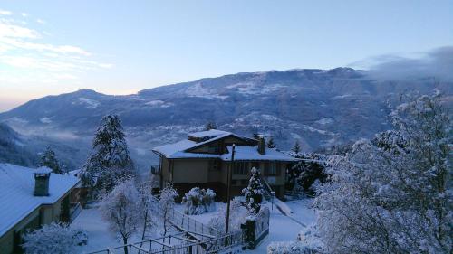 a house covered in snow with a mountain in the background at B&B I Baloss in Berbenno