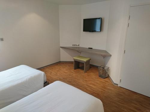 a room with two beds and a desk with a tv at H24 HOTEL in Le Mans