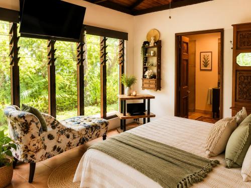 a bedroom with a bed and a chair and windows at Gunnadoo Holiday Hut with Ocean Views and Jacuzzi in Miallo