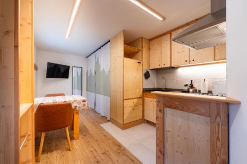 a kitchen with wooden cabinets and a table in a room at Dolomitihouse NOGHERA in Fiera di Primiero