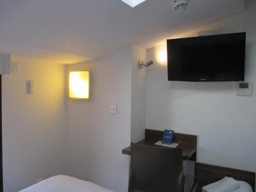 a hotel room with a bed and a tv on the wall at Hôtel le Pastel in Toulouse