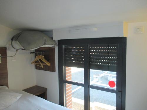 a bedroom with a window with blinds on a bed at Hôtel le Pastel in Toulouse