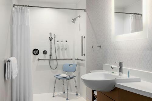 a bathroom with a sink and a shower with a chair at SpringHill Suites by Marriott Dayton Vandalia in Murlin Heights