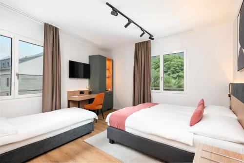 a hotel room with two beds and a desk at Tailormade Hotel AL GIARDINETTO Biasca in Biasca
