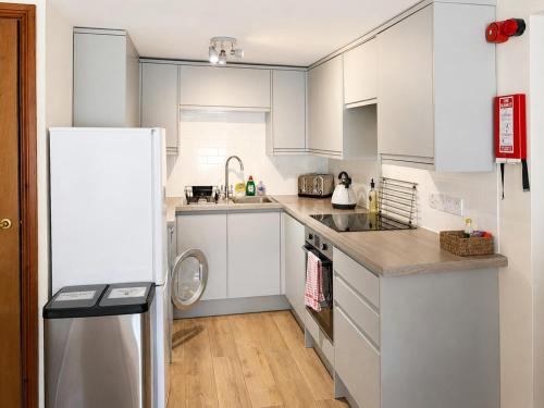 a kitchen with white cabinets and a refrigerator at Howgills Apartment 7 - Ukc9722 in Sedbergh