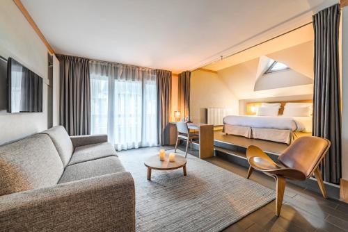 a hotel room with a couch and a bed at Hotel Le Morgane in Chamonix-Mont-Blanc