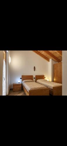a bedroom with two beds and a window at Baita PUPILLE in Osteria Alpina