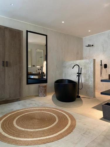 a bathroom with a large tub and a large mirror at Ubucuti Gorilla Lodge in Kinigi