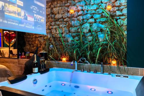a blue bath tub in a room with a stone wall at JADE Hammam & Jacuzzi in Brie-Comte-Robert