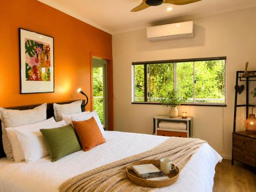 a bedroom with a large bed with orange walls at Sky: rainforest and ocean views with jacuzzi in Miallo
